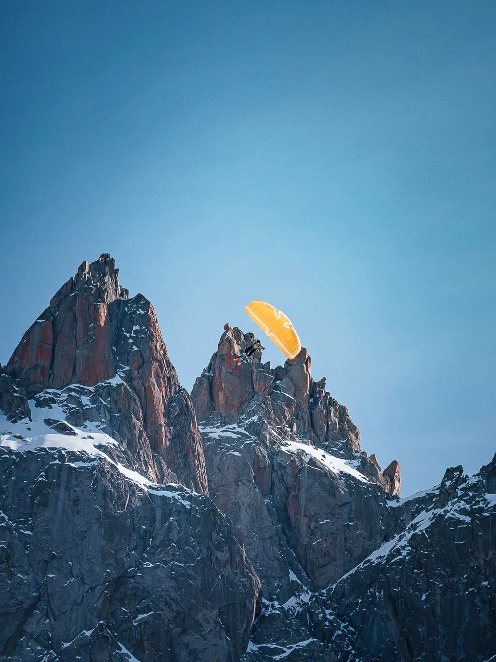Décollage en speedflying au sommet d’une arête rocheuse, voile orange